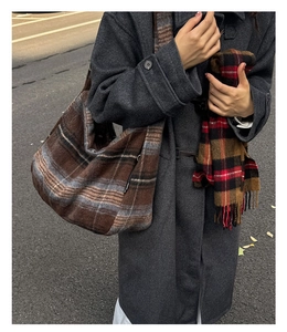 Detail of a large checkered wool tote bag styled with a red fringed scarf for winter