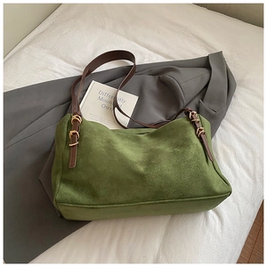 Detail of dark green suede tote bag with brown leather strap and gold hardware accents