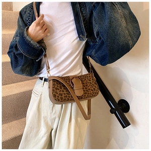 Detailed close-up of leopard print crossbody bag with vintage metal ring buckle and brown strap