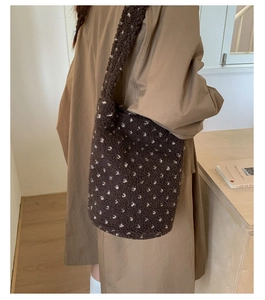Close-up of plush brown tote bag with white heart patterns and wide shoulder strap