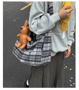 Detail of grey plaid wool tote bag featuring a brown leather rabbit charm and thick texture