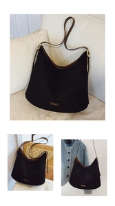 Detail of a large black canvas bucket bag with brown leather straps and gold hardware