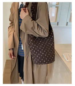 Fashionable dark brown plush tote bag with white dots worn by model in a cozy room