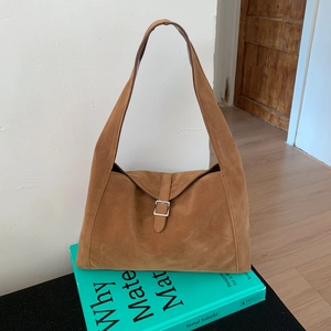 Close-up of vintage brown suede hobo bag with silver buckle on a lifestyle background