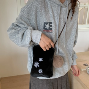Détail du petit sac bandoulière en peluche noire avec broderie flocon et pompon décoratif