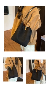 Detail view of large black suede tote bag with gold rotary lock on casual shoulder strap