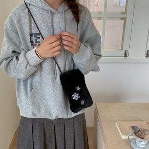 Détail d'un sac bandoulière en peluche noire avec broderies de flocons de neige