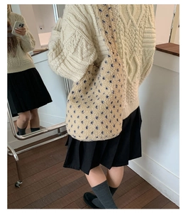 Detail of plush beige star pattern tote bag paired with cable knit sweater and skirt