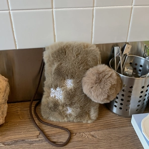 Détail d'un sac bandoulière en fausse fourrure marron avec broderie flocon et pompon