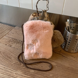 Détail d'un sac à bandoulière en peluche rose avec broderie de flocons de neige blancs