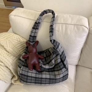 Detail of grey plaid wool tote bag with a soft plush texture and leather animal charm