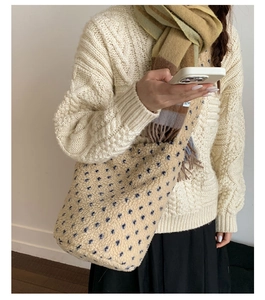 Detail of beige polka dot faux shearling bucket bag paired with a cozy winter scarf