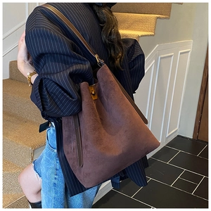 Detail of dark brown suede tote bag with leather strap and golden swivel lock buckle