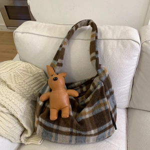 Detail of checkered hobo bag with brown rabbit leather charm on white sofa