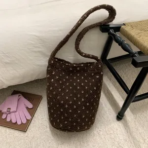 Detail of dark brown plush bucket bag with white heart dots in a cozy autumn setting