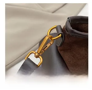 Detailed macro view of high-quality gold swivel hooks and brown suede strap on crossbody bag