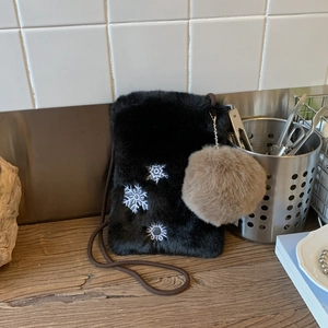 Détail du sac bandoulière en peluche noire avec broderie flocon et pompon décoratif