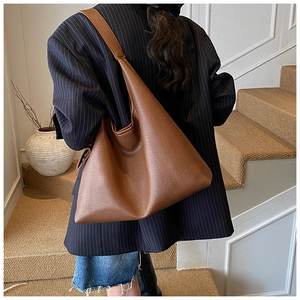 Detailed view of caramel brown leather tote bag showing lychee grain texture and soft drape