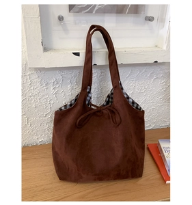 Détail du sac cabas en daim marron avec doublure à carreaux et noeud décoratif souple