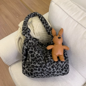 Detail of leopard print plush tote bag with brown faux leather rabbit charm on sofa