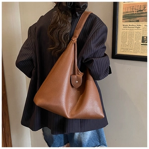Caramel brown leather tote bag with lychee texture and wide strap shown on shoulder