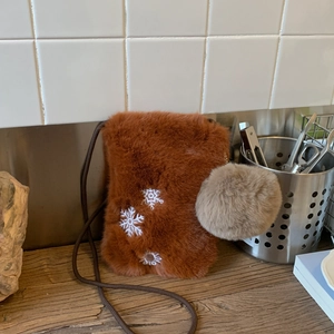 Détail du sac à bandoulière en fausse fourrure marron avec broderie flocon et pompon