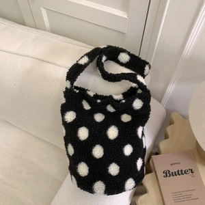 Texture détaillée d'un sac cabas en polaire à pois noir et blanc sur un canapé