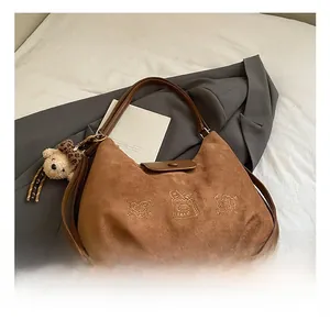 Detailed view of brown suede tote bag featuring cartoon embroidery and a plush bear pendant