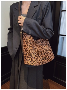 Detailed close-up of leopard print tote bag with brown leather strap and gold logo