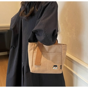 Détail du sac cabas en toile kaki avec broderie et anses tissées marron
