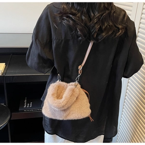 Gros plan d'un sac seau en peluche abricot avec bandoulière en cuir brun et boucle
