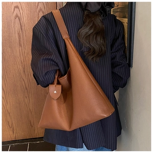 Brown lychee-textured leather hobo bag side view on shoulder with classic tag detail