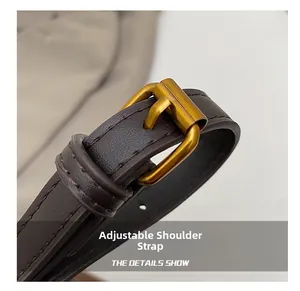 Detail of adjustable dark brown leather shoulder strap with golden metal buckle