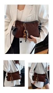 Detail of retro brown suede shoulder bag with black leather trim and wooden bead tassel