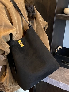 Minimalist black faux suede bucket tote bag with gold buckle and leather strap