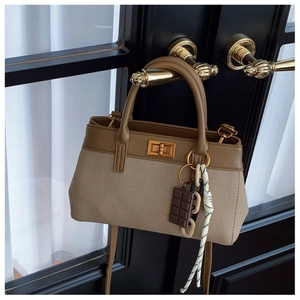 Detail of beige canvas bucket bag with brown leather trim on vintage door handle