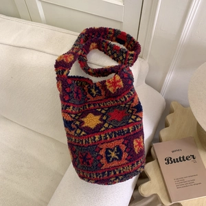 Gros plan sur un sac seau en peluche avec motifs ethniques géométriques colorés et bandoulière