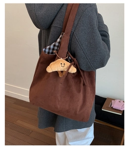 Détail du cabas en daim marron avec charm croissant en peluche et doublure à carreaux