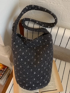 Minimalist dark grey faux shearling bucket bag with white polka dots for commuting