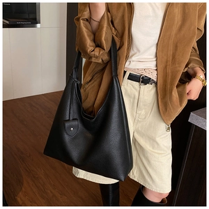 Close-up of a black lychee texture leather hobo bag with a stylish snap-button pocket detail