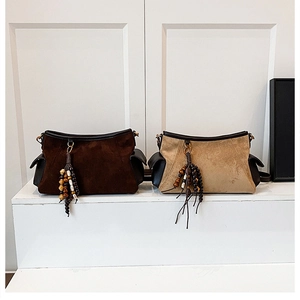 Close-up of bohemian suede underarm bags with colorful beaded tassel charms and side pockets