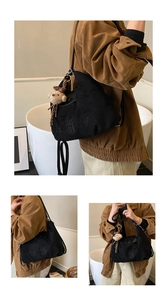 Close-up of black canvas tote bag with cartoon embroidery and a brown plush bear charm