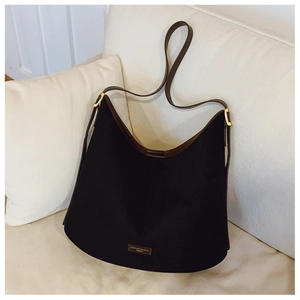 Detailed macro view of the black textured hobo bag with brown leather accents and metal logo