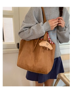 Détail du sac cabas en daim marron avec doublure à carreaux et breloque croissant en peluche