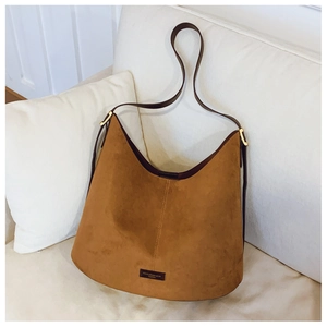 Detail of tan suede hobo bag with dark brown leather strap and gold hardware accents