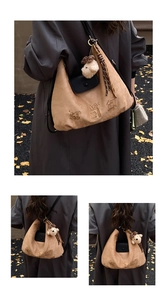 Detail of tan suede tote bag with black flap and plush dog charm in autumn setting