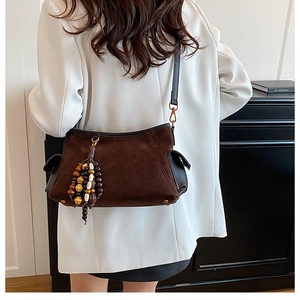 Detail of dark brown suede shoulder bag featuring retro wooden bead charms and side pockets