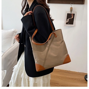 Detail of khaki tote bag with leather corners shown in a professional commute style