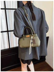 Detail of olive green canvas bucket bag featuring chic leather trim and woven chain strap
