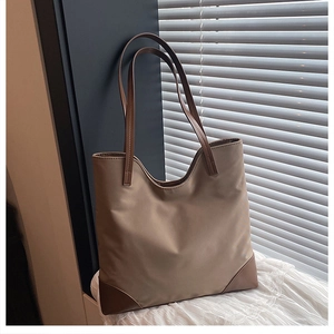 Detail of khaki tote bag showing water-resistant nylon fabric and brown leather straps